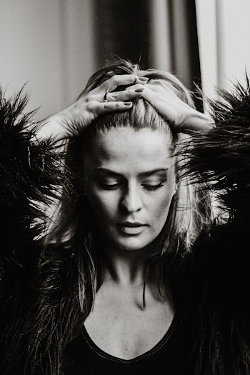 Grayscale Photo of Woman Looking Down While Posing With Her Hands on Her Head