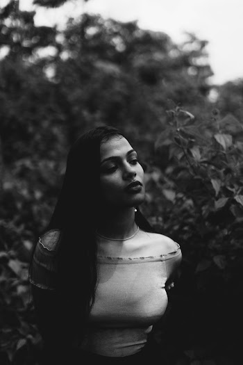 Grayscale Photo of Woman Posing Next to Plants While Looking Away