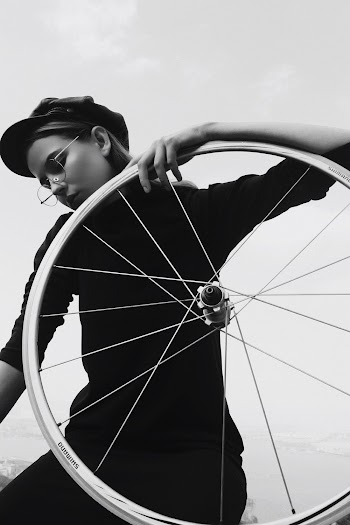 Grayscale Photo of Woman Posing While Holding a Bicycle Wheel and Looking Down