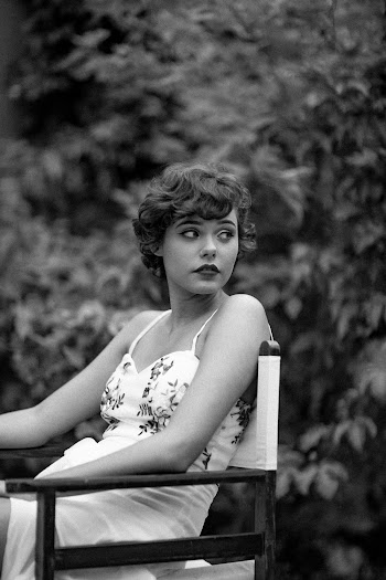 Grayscale Photo of Woman Sitting on  Wooden Armchair Looking Back