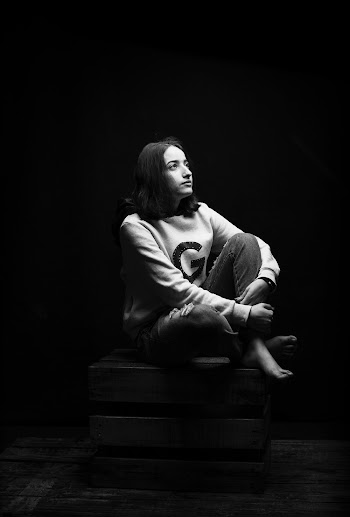 Grayscale Photo of Woman Sitting on Wooden Crate