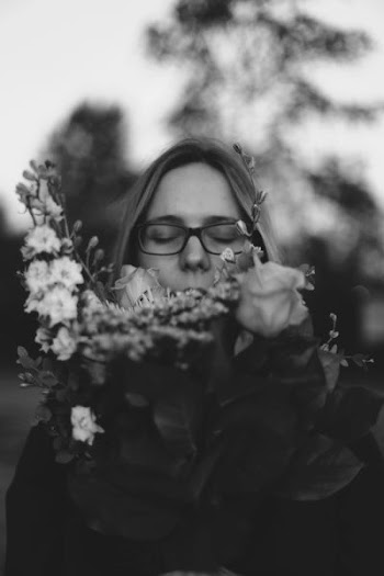 grayscale photo of woman smelling flower