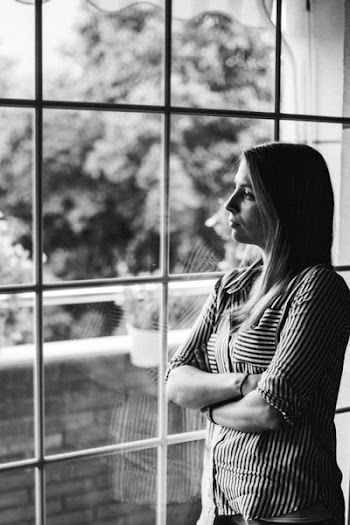 Grayscale Photo of Woman Standing Beside Mirror