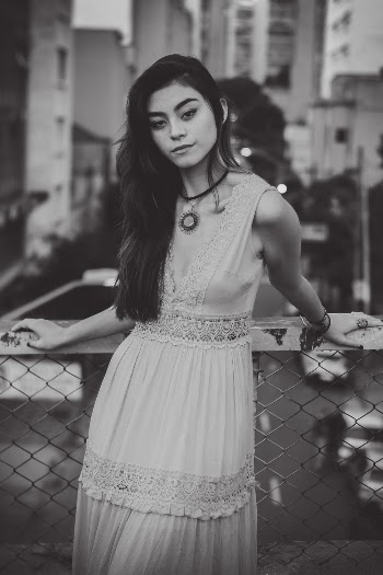 Grayscale Photo of Woman Standing in Front of Chain-link Fence
