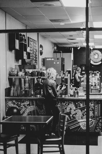 Grayscale Photo of Woman Standing Near Counter