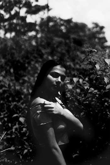 Grayscale Photo of Woman Standing Near Plants