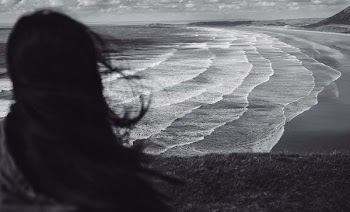 grayscale photo of woman standing near seashore