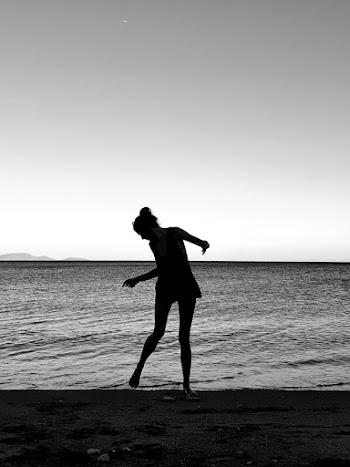 Grayscale Photo of Woman Standing on Shore Looking at Her Feet