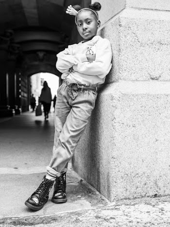 Grayscale Photo of Young Girl Leaning on Wall Posing with Her Arms Crossed