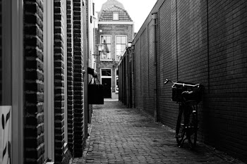 Grayscale Photograph of Bike Parked Beside Wall