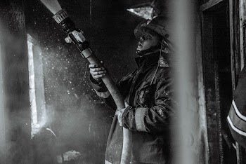 Grayscale Photography of a Fireman Holding a Hose