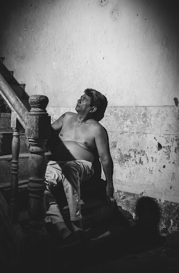 Grayscale Photography of a Shirtless Man Sitting on Stairs