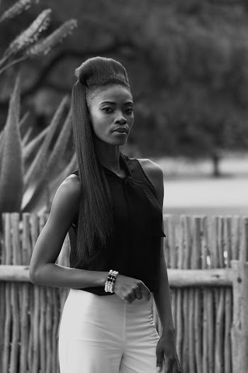 Grayscale Photography of a Woman Wearing a Black Top Standing Near a Wooden Fence