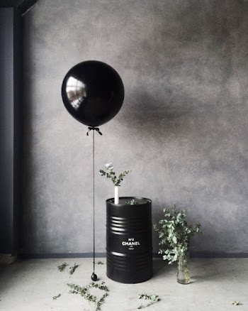 Grayscale Photography of Balloon Beside Chanel Metal Barrel