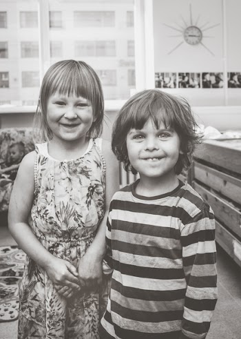 Grayscale Photography of Boy and Girl Standing Near Wooden Bed Inside Room