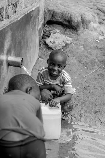 Grayscale Photography of Boy Holding Jerrycan