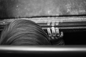 grayscale photography of boy standing in front of glass mirror