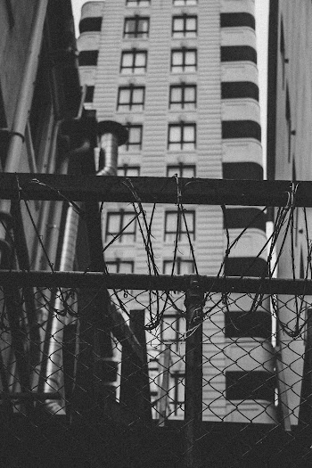 Grayscale Photography of Chain Link Fence Near Building