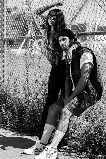 Grayscale Photography of Couple Standing Against Fence