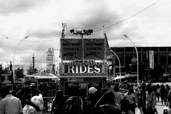 Grayscale Photography of Crowd Walking Near Rides Booth
