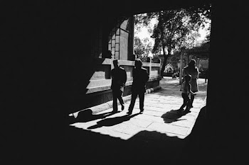 grayscale photography of four persons standing near building