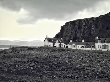 grayscale photography of houses near rocky mountain and body of water