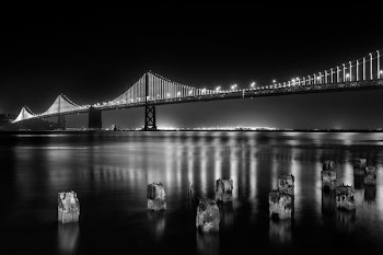 grayscale photography of lightened full-suspension bridge