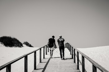 Grayscale Photography of Man and Woman Crossing Bridge