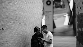 Grayscale Photography of Man and Woman Standing Near Concrete Wall