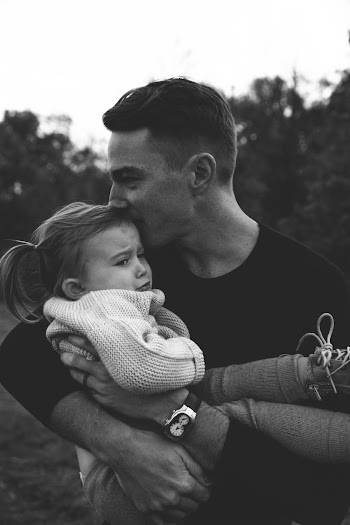Grayscale Photography of Man Carrying Crying Baby While Kissing Her Head