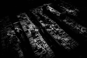 grayscale photography of man finding books inside library