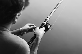 Grayscale Photography of Man Holding Fishing Rod