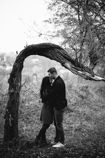 Grayscale Photography of Man Kissing Forehead of Woman Standing Near Tree