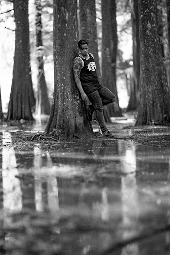 Grayscale Photography of Man Leaning Against Tree