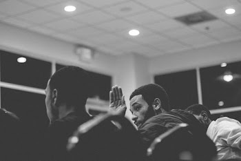 grayscale photography of man raising his hand