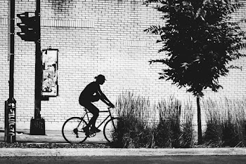Grayscale Photography of Man Riding Bicycle