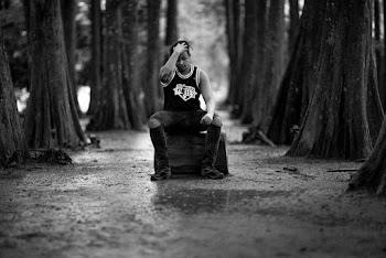 Grayscale Photography of Man Sitting Beside Trees