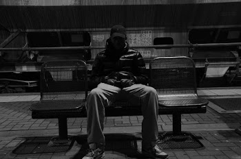 grayscale photography of man sitting down on metal bench