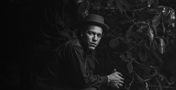 Grayscale Photography of Man Sitting Near Plants