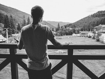 Grayscale Photography Of Man Standing At Balcony
