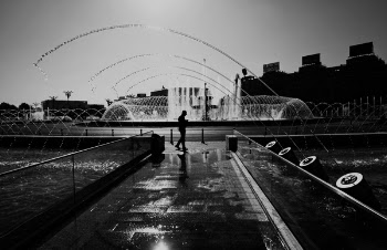 Grayscale Photography of Man Standing Near Fountain
