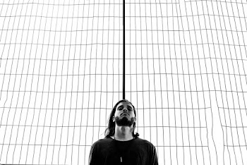 Grayscale Photography of Man Standing Near Wire Grille