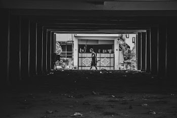 Grayscale Photography of Man Walking Beside Gate