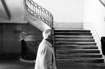 Grayscale Photography of Man Walking Near Staircase