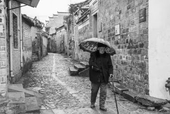 Grayscale Photography of Man Walking While Holding Umbrella