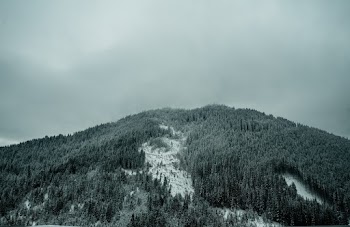 Grayscale Photography of Mountain Under Cloudy Sky