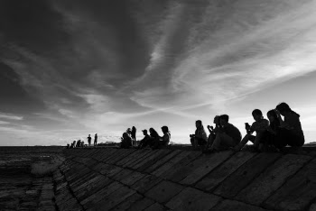 Grayscale Photography of People Sitting on Seawall