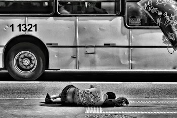 grayscale photography of person laying on ground near bus