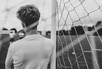 Grayscale Photography of Person Leaning on Goal