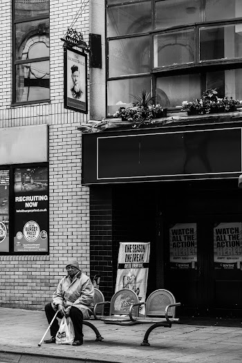 Grayscale Photography of Person Sits on Chair Beside Road